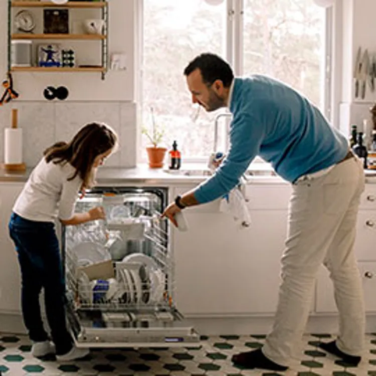 father and daughter putting dishes in dishwasher