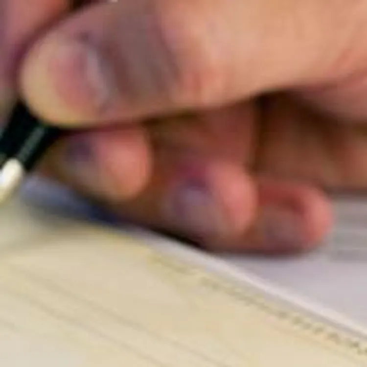 hand holding a pen writing on a check