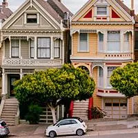 row of houses on an inclined street with cars parked in front