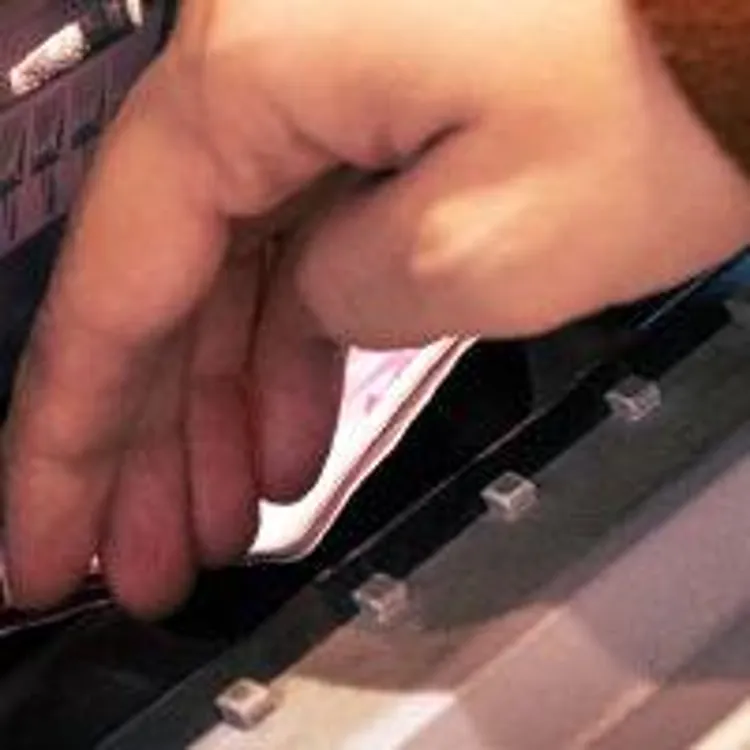 a person's hand putting cash deposit at an atm
