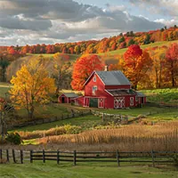 red barn in the middle of a farm with autumn trees in the background