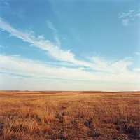 vast expanse of land with a clear blue sky and wispy white clouds