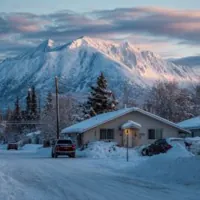 mountain behind a bungalow with a parked pickup truck in winter