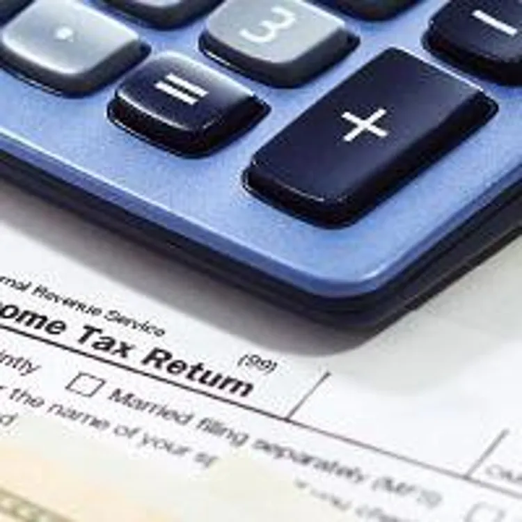 u.s. currency, pen, calculator and paperclip placed on top of a tax form