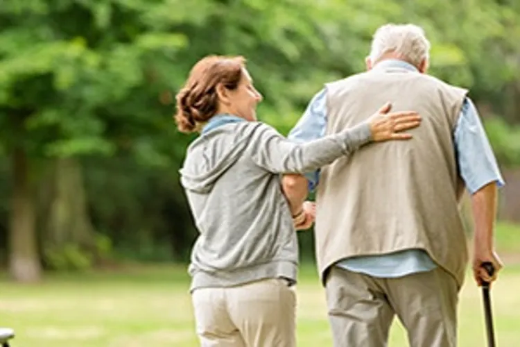 caregiver helping a senior man walk
