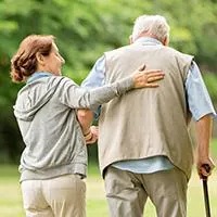 caregiver helping a senior man walk