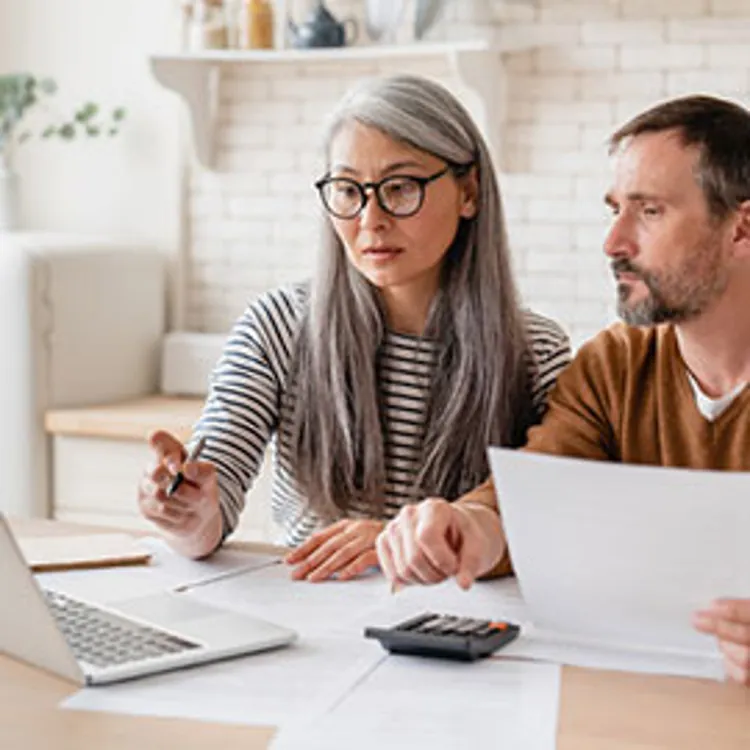 mature couple looking at a laptop while reviewing paperwork