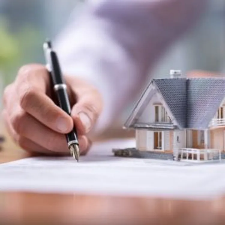 a toy model home placed on top of a paper being signed