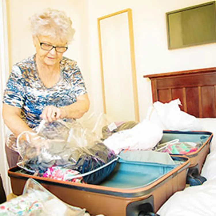 lady putting clothes from luggage into large plastic bag