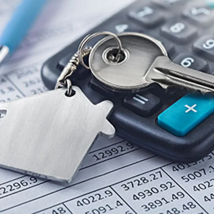 house key on top of a calculator and mortgage document