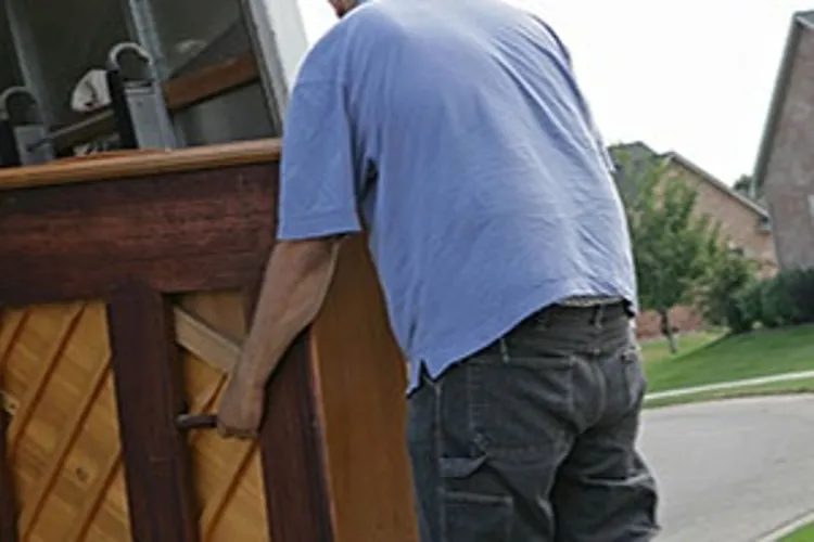 two men moving piano onto truck