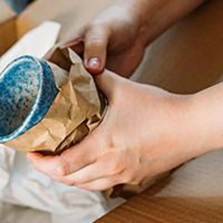 woman wrapping and packing a mug in moving box