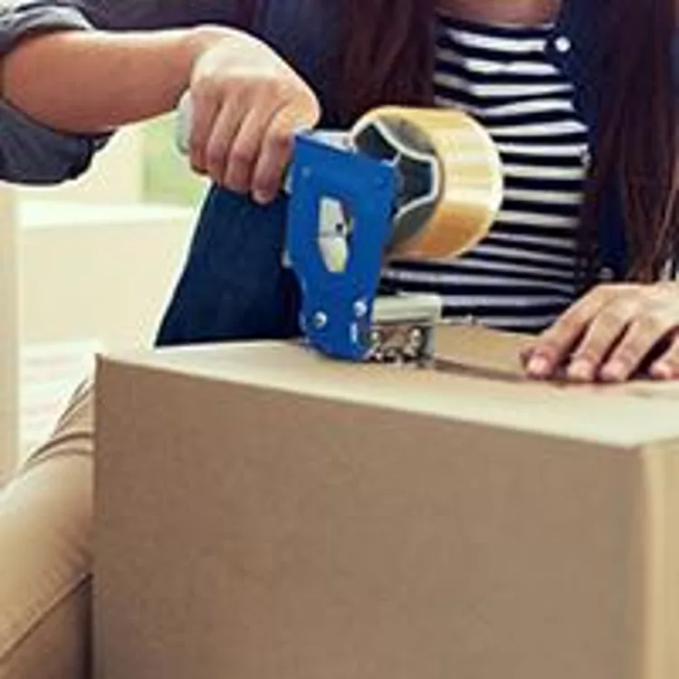 woman sitting on floor taping a moving box