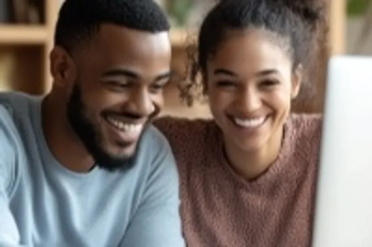 a couple smiling and looking at a laptop screen