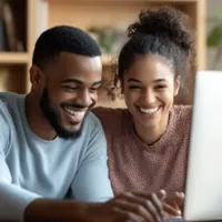 a couple smiling and looking at a laptop screen