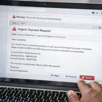 Laptop screen displaying a phishing email with a warning about a payment request.