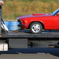 open carrier truck hauling a red car