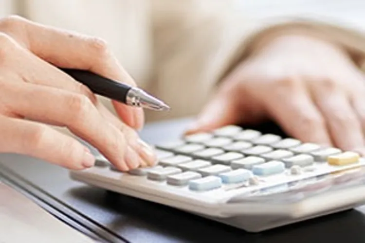 person making calculations looking at papers with a model house on the side