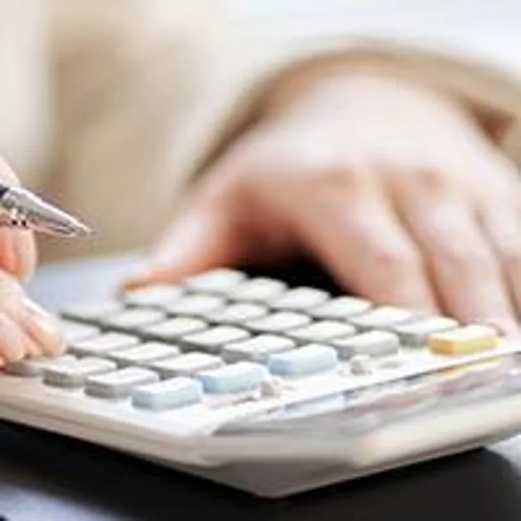 person making calculations looking at papers with a model house on the side