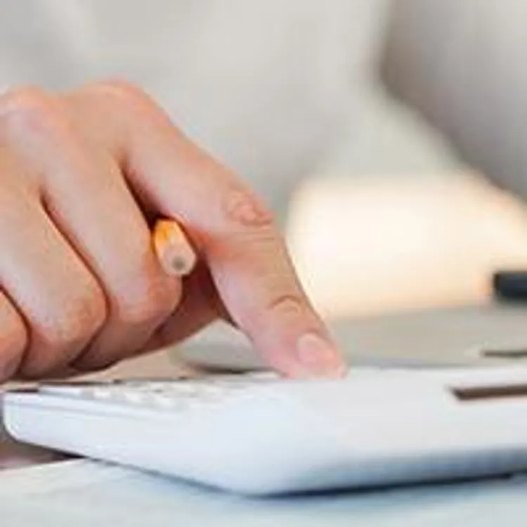 person using calculator with miniature house