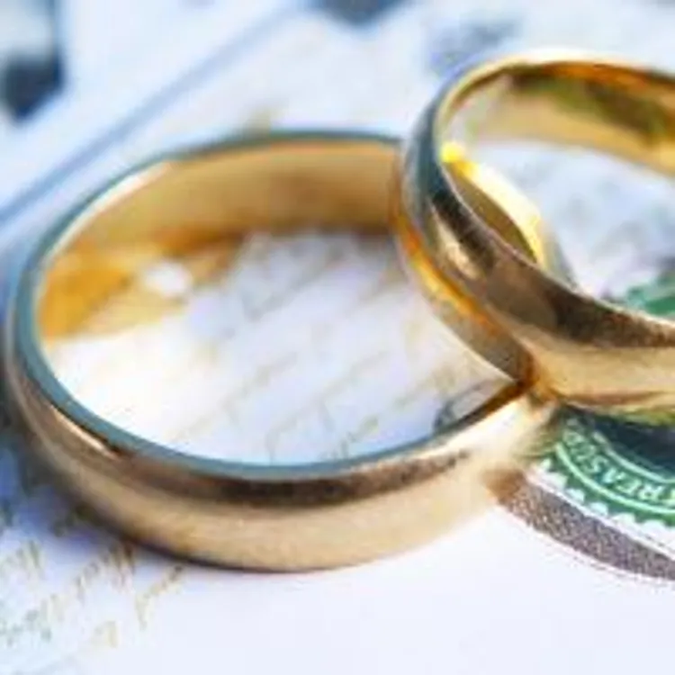 two gold wedding rings on top of paper bills