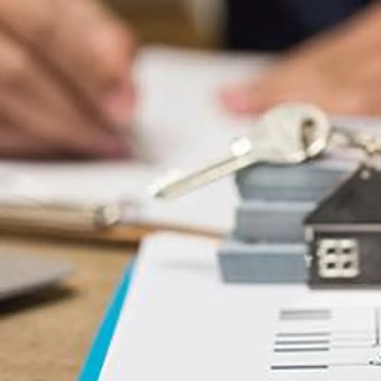 miniature house with man signing documents in background
