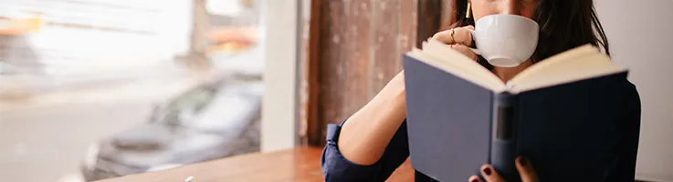 girl in a coffee shop drinking coffee and reading a book