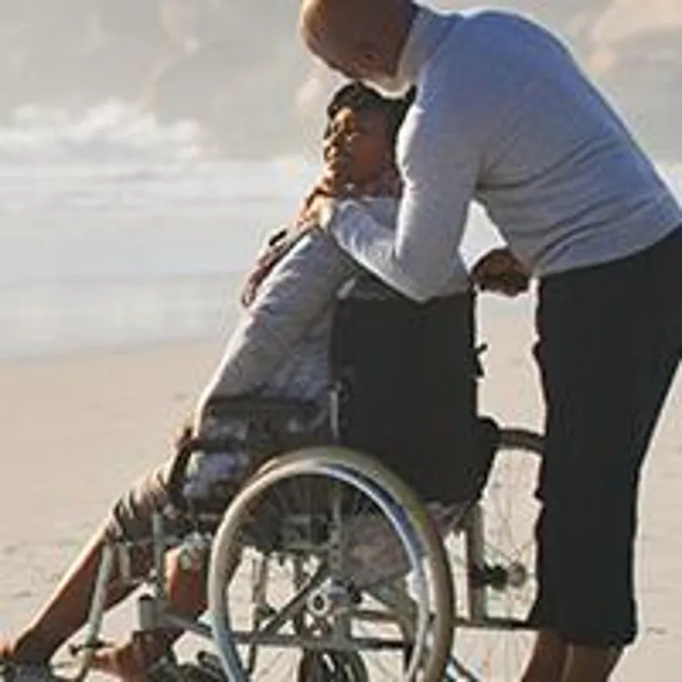 husband hugging wife in wheelchair at the beach