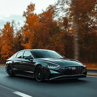 black hyundai sonata along a road lined with trees in autumn colors