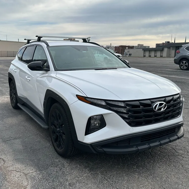 White SUV parked in an urban parking lot under a cloudy sky.