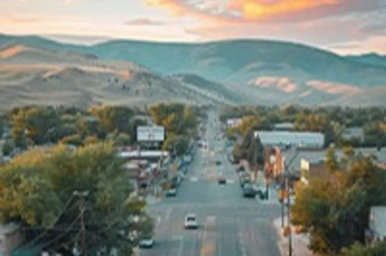 A wide street with trees on the sidewalk leading towards mountains in the background