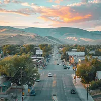 A wide street with trees on the sidewalk leading towards mountains in the background