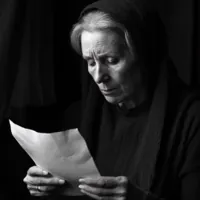 an elderly woman reading a piece of paper