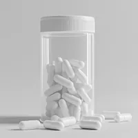 white capsules within and without a transparent container with a white cap