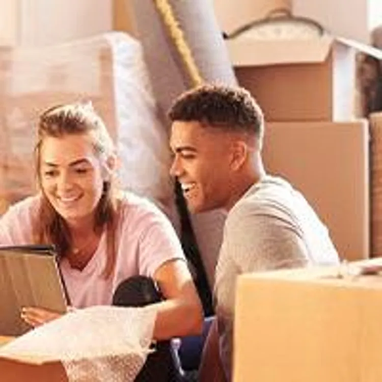 couple using tablet with moving boxes around them