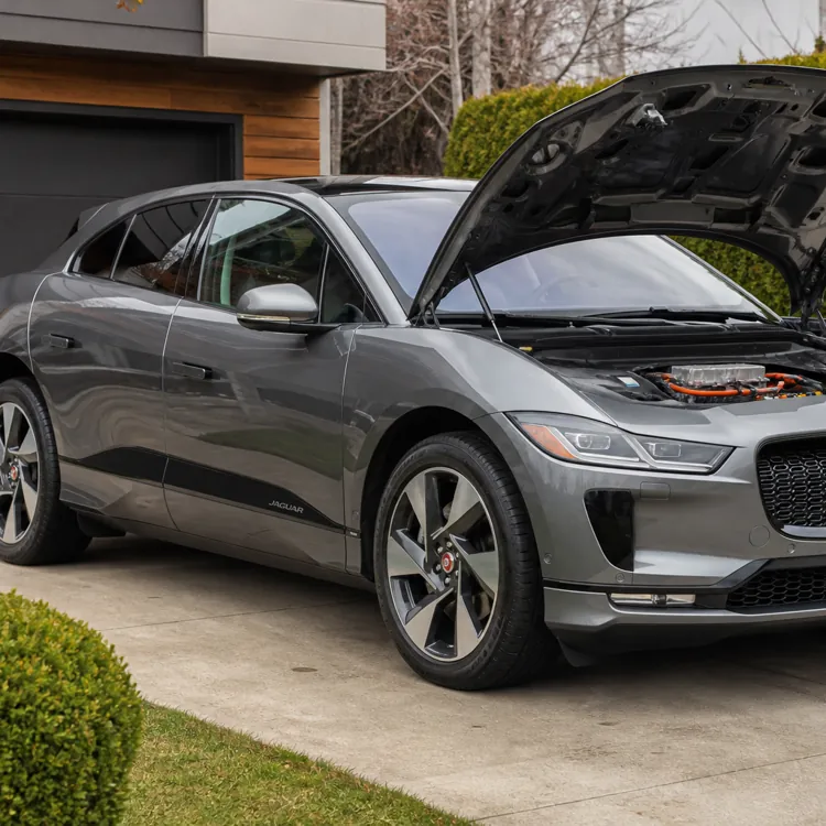 Silver electric car with its hood open parked on a residential driveway