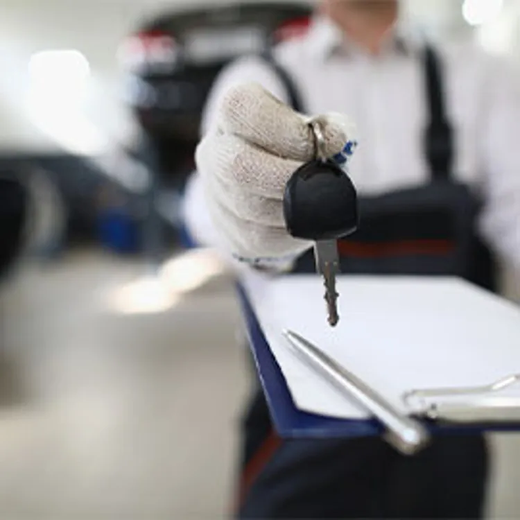 auto mechanic holding a checklist and handing car keys