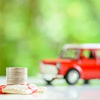 stacked coin in front of red land rover toy car