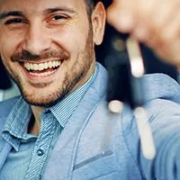 man holding keys out the window of new car