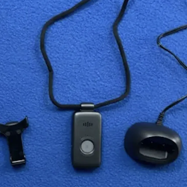 Medical alert device with lanyard, charging dock, clip, and instruction manual on blue surface