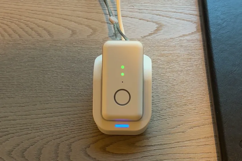 Close-up of the Pearl pendant in its cradle with two green battery lights on the pendant and a blue light on the cradle