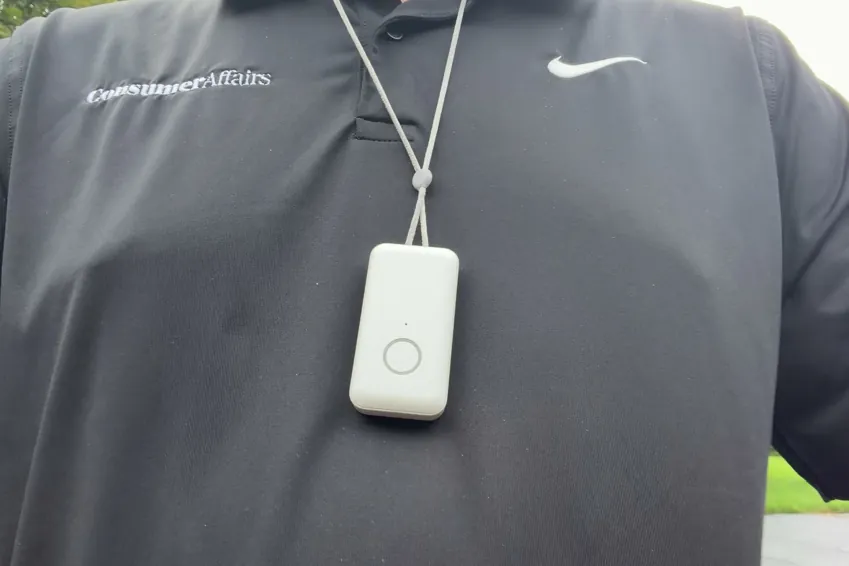 LifeStation Pearl pendant hanging on its gray lanyard over a black ConsumerAffairs polo, outdoors