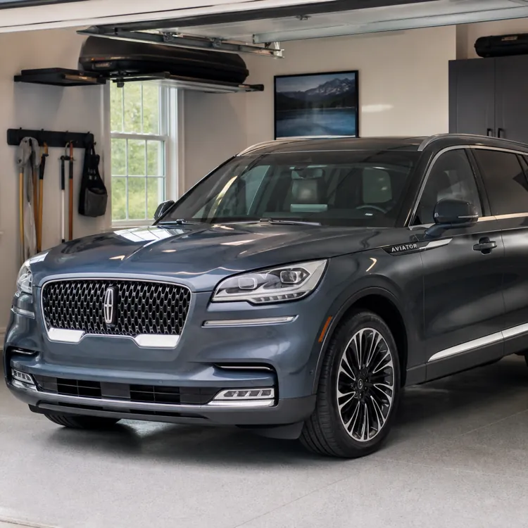 Gray SUV parked inside a clean residential garage with tools and cabinets on the wall