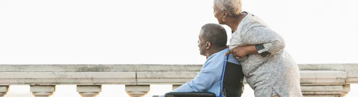 older woman pushing older man in wheelchair
