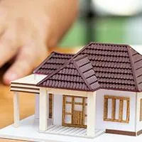 man filling out paper behind model home