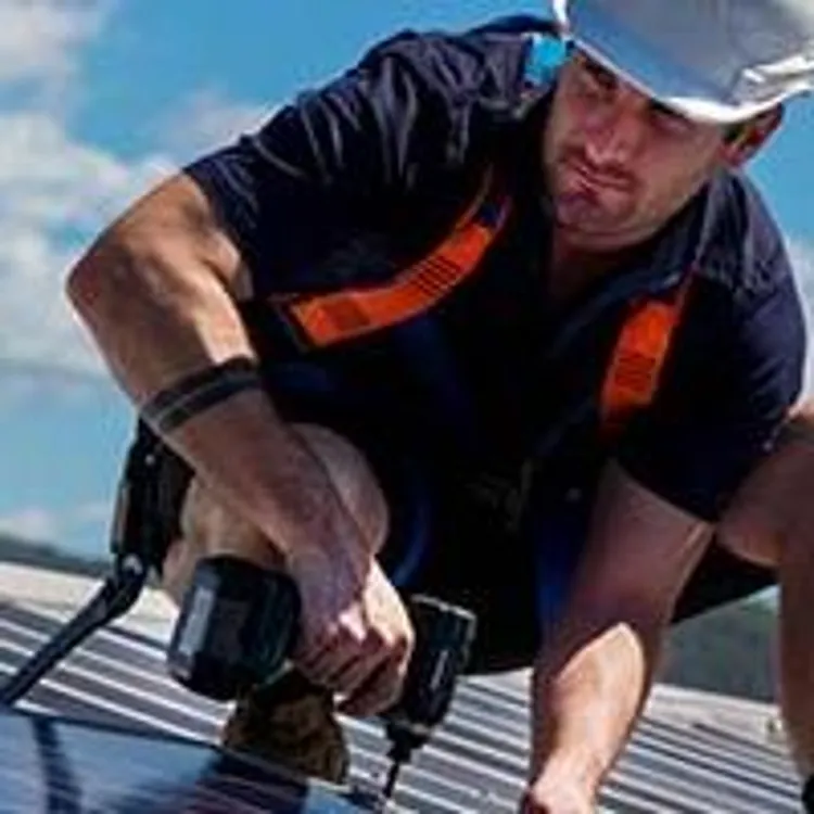 man screwing solar panels on roof
