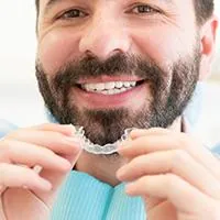 man smiling holding clear aligner