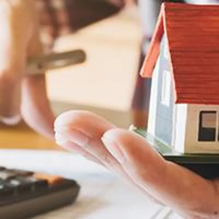 man using calculator holding model home