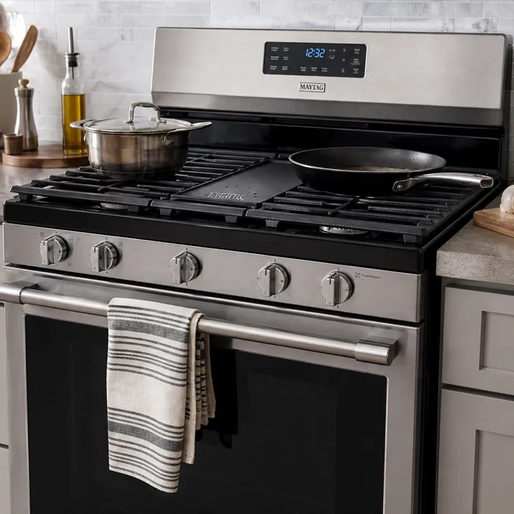 Stainless steel gas stove with pots and utensils in a modern kitchen setting