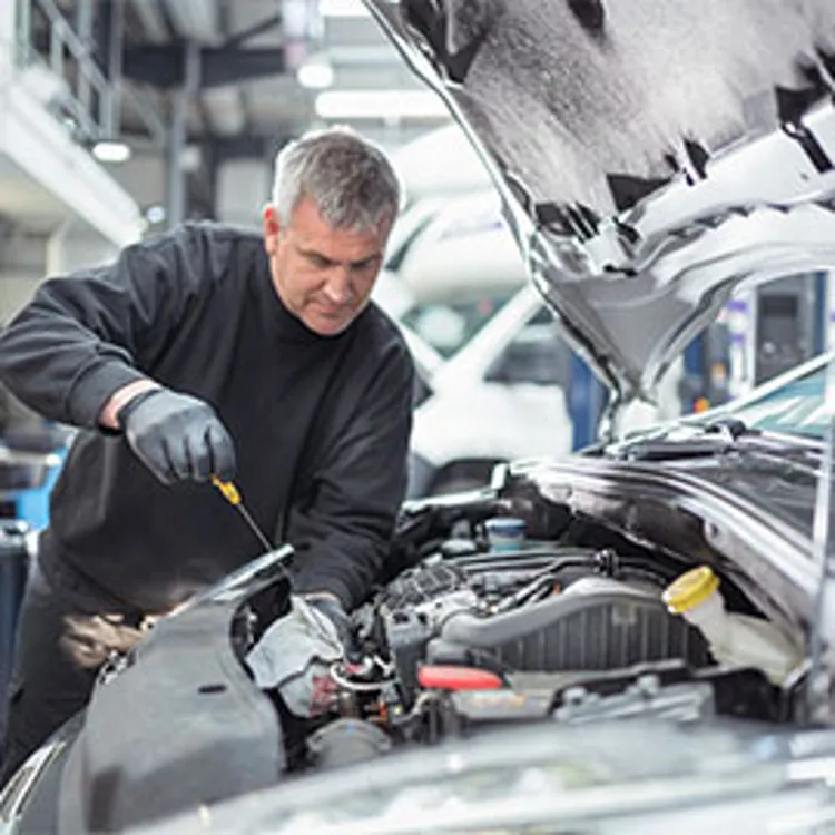 auto mechanic checking engine oil